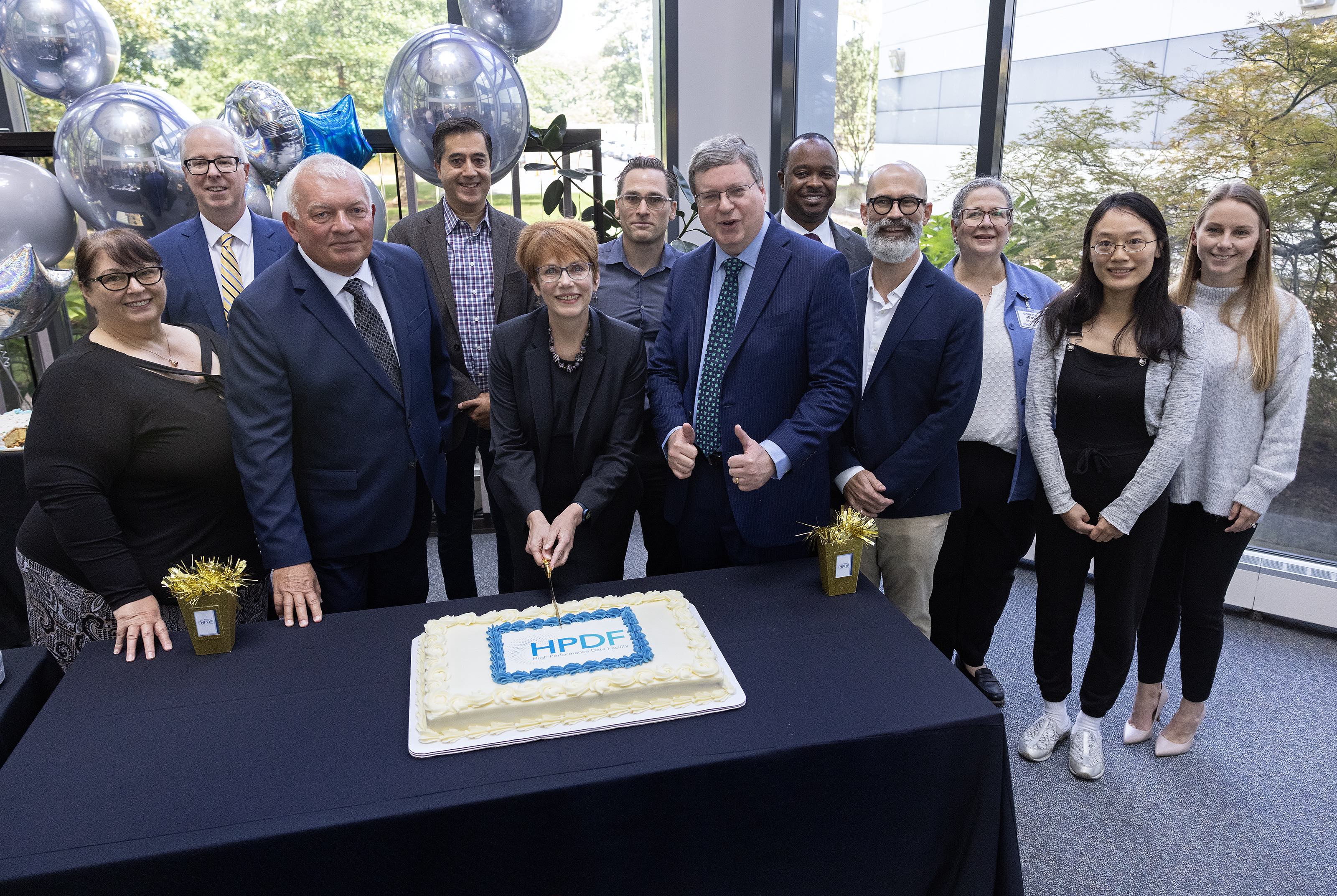 HPDF Lead Amber Boehnlein cute the celebratory HPDF Event cake with the proposal team, with Chief Research Officer David Dean.